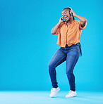 Black woman, headphones and dancing to music with singing in a studio. Audio streaming, radio and happy female person with blue background and excited from celebration and freedom with hip hop song