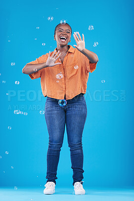 Buy stock photo Excited, happy and black woman on blue background with bubbles for happiness, joy and have fun. Playful, smile and isolated African person in studio with soap bubble for cheerful, magic and aesthetic
