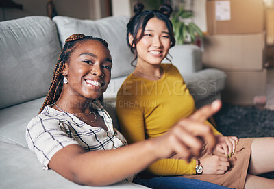 Buy stock photo Pointing, friends and women in home for visit, bonding and conversation in living room together. Hand gesture, showing house decor and black female and Asian person in lounge to relax on weekend