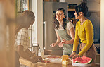 Happy, friends and women cooking pizza in kitchen, bonding and having fun together in home. Smile, girls and baking food, margherita and salami bread at lunch, cheese on meat and watermelon at brunch