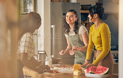 Buy stock photo Happy, friends and women cooking pizza in kitchen, bonding and having fun together in home. Smile, girls and baking food, margherita and salami bread at lunch, cheese on meat and watermelon at brunch