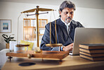 Scales, justice and man in office with laptop for working in law firm, court research or search online for legal policy or rules. Judge, attorney or mature businessman with communication on computer 