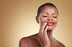 Makeup, beauty and a black woman with hands on mouth in studio for skin care, glow and cosmetics. Face of african model person with shine on lips, dermatology and mockup space on beige background