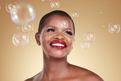 Buy stock photo Smile, makeup and bubbles with face of black woman in studio for cosmetics, spa treatment and luxury. Skincare, dermatology and self care with model on gold background for glow, facial and beauty