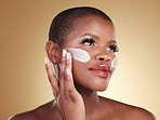 Application, skincare and face cream for black woman in studio for dermatology or cosmetic wellness on brown background. Beauty, hand and model with facial, sunscreen or collagen, mask or scrub