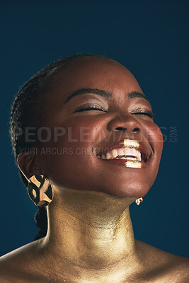 Buy stock photo Gold makeup, face and black woman laughing at funny creativity, facial cosmetics paint and beauty art design. African culture joke, comedy or glamour person with creative face glow on blue background