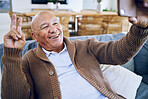 Selfie, peace sign and happy senior man on sofa smile for social media, online post and profile picture. Technology, retirement and elderly person take photo with emoji, hand gesture or relax in home