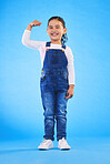 Young, girl child and champion, winner and emoji with happiness, strong and excited isolated on blue background. Power, muscle and winning with success, body language and happy kid in a studio