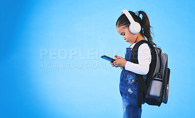 Buy stock photo Music, backpack and child on blue background with phone ready for school, learning and education. Kindergarten, studio and young girl with bag on smartphone for streaming song, audio and radio