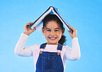 School, head and portrait of kid with book for knowledge or learning isolated in a studio blue background. Clever, smart and young girl child with notebook happy for education, story or reading