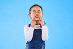 Child, funny, face and girl with silly, goofy or facial expression on blue background in studio with fashion for children. Kid, portrait and tongue out of mouth in joke, humor or emoji for comedy