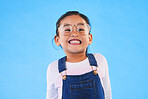 Girl kid, glasses and vision in studio with smile, medical and thinking for eye care by blue background. Female child, test spectacles and young fashion model with lens, frame and excited for health