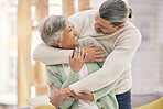 Happy elderly couple, hug and relax with love in living room bonding, romance or embrace together at home. Mature man and woman smile in happiness for loving relationship, affection or quality time