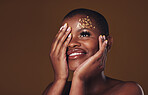 Art, smile and black woman with gold makeup on brown background, glitter and cosmetics mockup. Beauty shine, glow and African model in studio space for fashion, aesthetic freedom and luxury skincare.