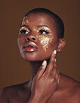 Art, aesthetic and black woman with gold makeup and brown background with glitter, paint and cosmetics. Shine, glow and African model in studio for beauty, fashion and  freedom in luxury skincare.