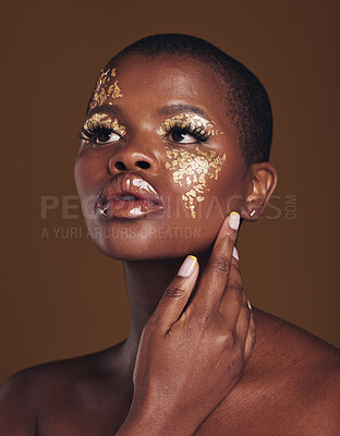 Buy stock photo Art, aesthetic and black woman with gold makeup and brown background with glitter, paint and cosmetics. Shine, glow and African model in studio for beauty, fashion and  freedom in luxury skincare.