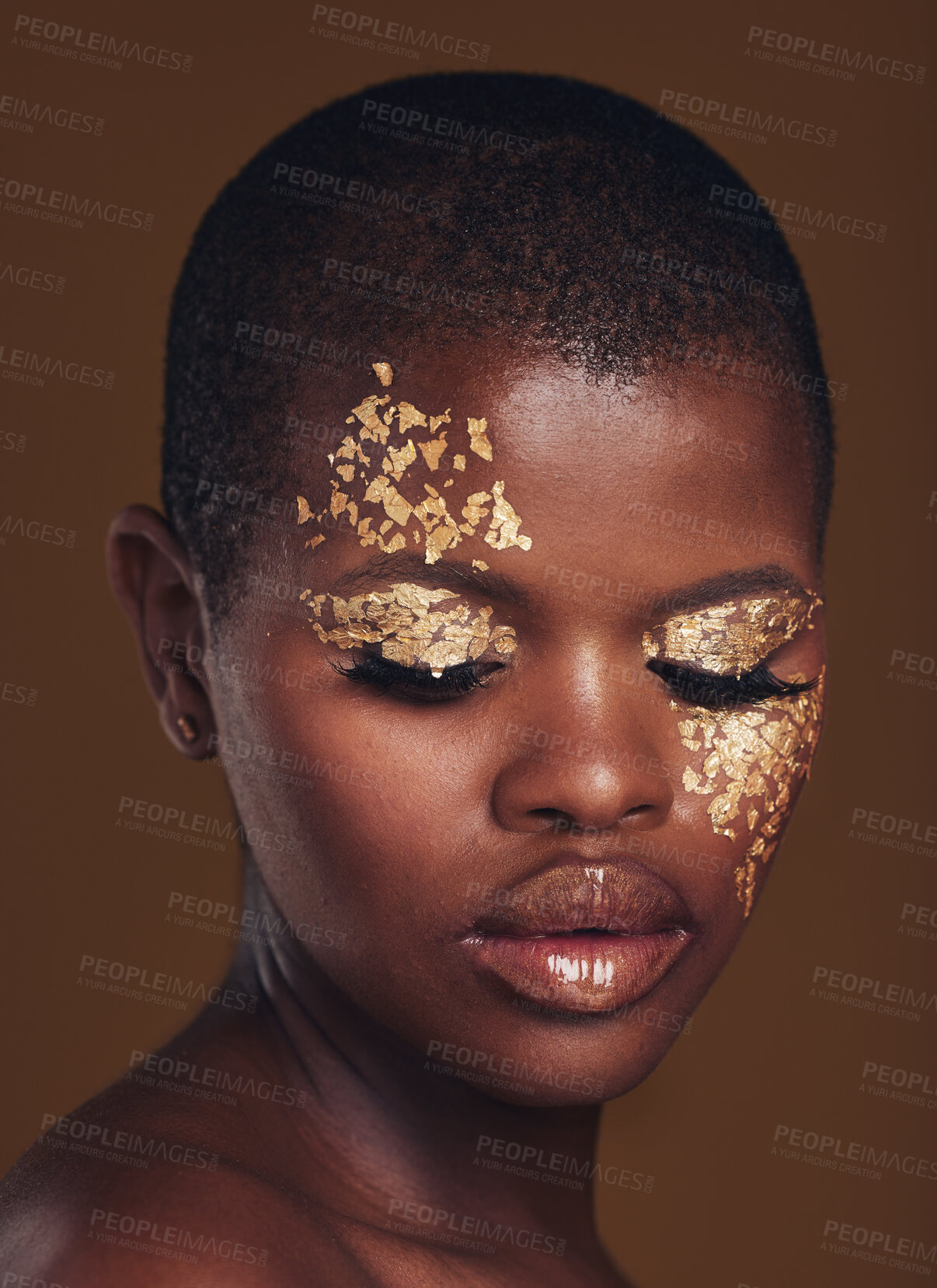 Buy stock photo Gold flakes, beauty and black woman with face closeup with makeup and cosmetics in studio. Brown background, African female model and glitter with golden shine and glow from facial paint sparkle