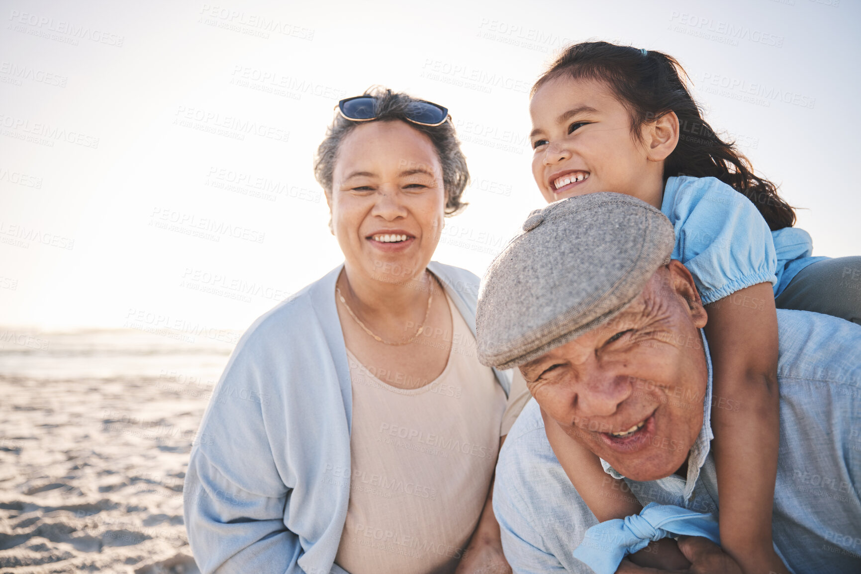 Buy stock photo Fun, beach and girl playing with her grandparents on a family vacation, adventure or holiday. Happy, smile and child on a piggyback ride and bonding with her grandmother and grandfather by the ocean.