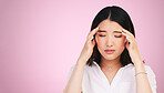 Asian woman, headache and stress in anxiety, burnout or tired against a pink studio background. Frustrated, upset or unhappy female person with migraine, injury or mental health pain on mockup space