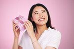 Woman, gift box and thinking in studio of birthday, surprise and happiness on face for celebration in pink background. Present, package and curious Asian model with a guess for giveaway or promotion