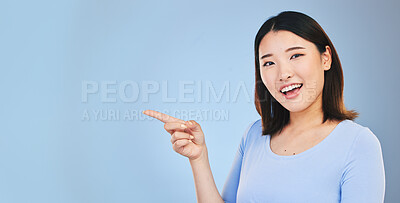 Buy stock photo Asian woman, point and studio portrait with space, mockup and happy for promotion by blue background. Japanese student, girl and smile for review, opinion or feedback with choice, decision and sign