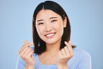 Happy asian woman, portrait and love sign or hand gesture in romance against a blue studio background. Face of female person smile in happiness with loving emoji, icon or symbol for valentines day