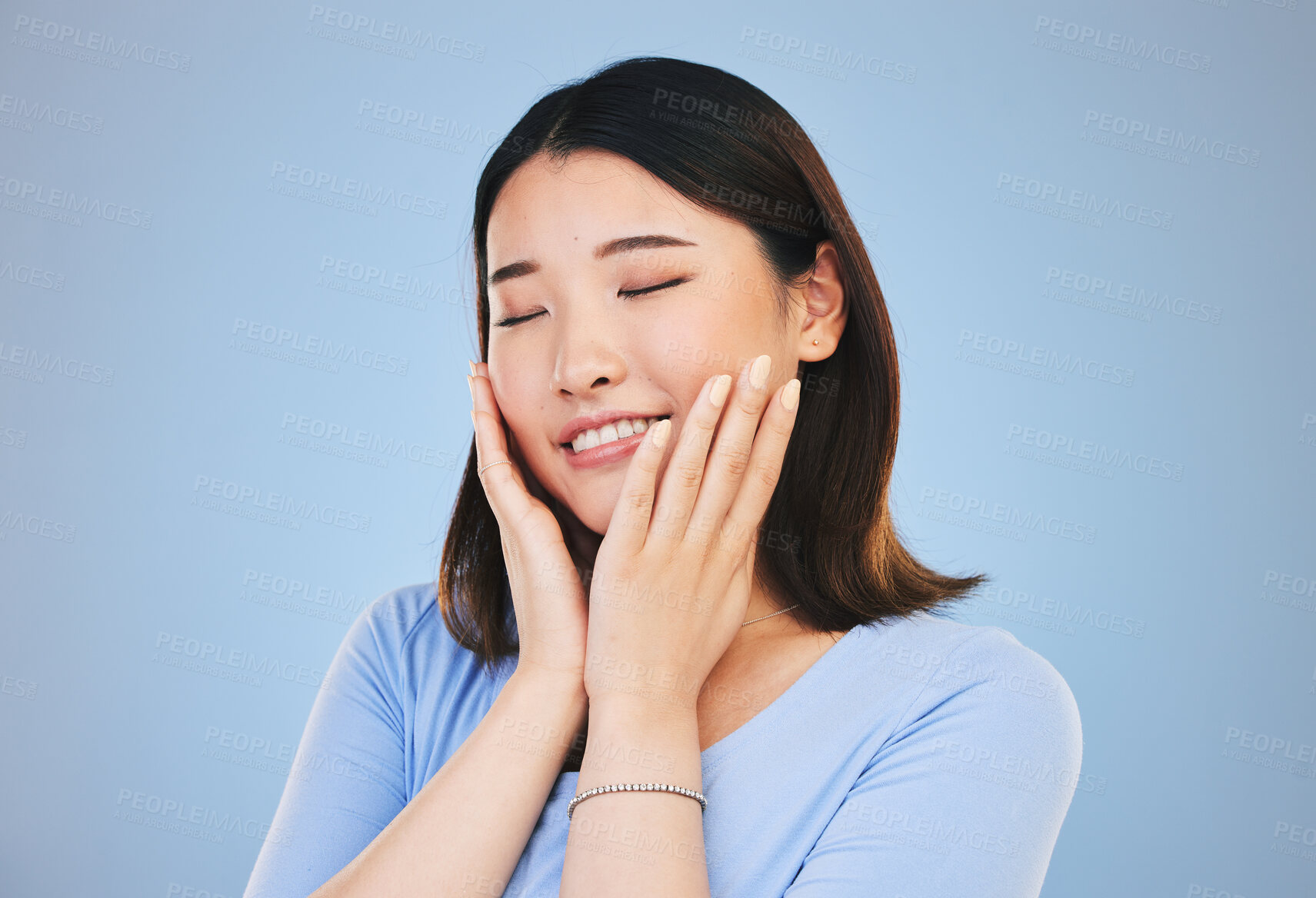 Buy stock photo Face, beauty and skincare with an asian woman on a blue background for natural treatment or cosmetics. Smile, makeup and freedom with a young model touching her skin in satisfaction in a studio