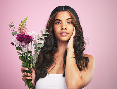 Buy stock photo Woman, flowers and portrait in studio for skincare, cosmetics and natural aesthetic on pink background. Face, model and eco beauty with floral plants, sustainability and bouquet for vegan dermatology