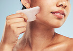 Skincare, gua sha and woman with face massage on studio for anti aging, wellness and circulation on grey background. Stone, facelift and beauty model with rose quartz for lymphatic drainage facial