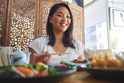 Buy stock photo Asian, food and woman at a restaurant eating for dinner or lunch meal using chopsticks and feeling happy for nutrition. Plate, young and person enjoy Japanese cuisine, noodles or diet at a table