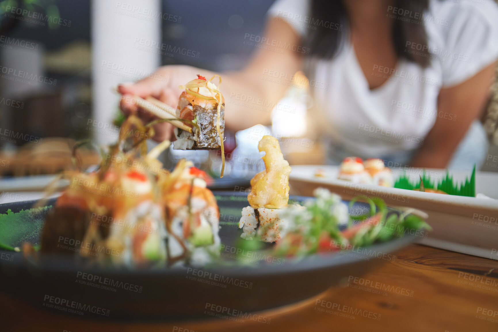 Buy stock photo Hand, closeup and chopsticks in sushi restaurant for diet, fine dining and party with catering platter. Person, healthy fish and salmon with culture, traditional or fast food in diner, bar or store