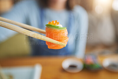 Buy stock photo Sushi, eating food and hand with chopsticks at restaurant for nutrition and health. Closeup of a person with wooden sticks for dining, Japanese culture and salmon cuisine with creativity on fish