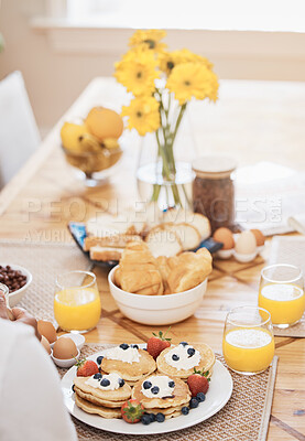 Buy stock photo Pancakes, breakfast and orange juice on table in home in the morning. Bread waffle, hands and fruits for eating, healthy diet and strawberry cream in wellness nutrition, blueberry food and egg meal.