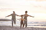 Travel, freedom and a family at the beach during sunset for flying, playing and bonding at the ocean. Smile, holiday and an interracial child, mother and father at the sea for a vacation or summer