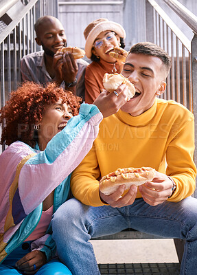 Buy stock photo Friends, city and feeding food outdoor for happiness, funny laugh and fun on stairs. Diversity, eating and gen z group of men and women with a hotdog on a date, adventure and freedom in urban town