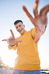 Frame, summer and a man with hands at the beach with happiness, freedom and creativity. Smile, portrait and a young person at the sea with a gesture for perspective on a vacation at the ocean