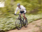Fast, cycling and man on a bike in nature for fitness, sports or a competition. Energy, mountains and a male cyclist on a bicycle in the woods with speed for exercise, cardio or training in a forest