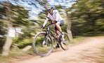 Nature blur, mountain bike and sports man cycling, action and ride bicycle for cardio, fitness or outdoor exercise. Low angle, fast motion and extreme cyclist training, speed and danger risk in woods