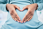 Heart, woman hand and pregnancy love in a hospital with mama, stomach and baby care. Wellness, abdomen and pregnant female person with emoji and happy mom gesture of a check for health of a mother