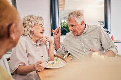 Buy stock photo Food, retirement and a senior couple in an assisted living home while eating a meal for nutrition. Cute, love or smile with a happy elderly man feeding his wife in the dining room of a house