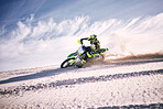 Bike, sky and speed with a man on sand riding a vehicle in the desert for adventure or adrenaline. Motorcycle, training and dust with an athlete outdoor in nature for freedom, power or competition