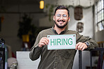 Portrait, man and we are hiring sign with recruiting, happy and smile from business owner. Male person, store and entrepreneur with recruitment poster and job search signage with manager and employee