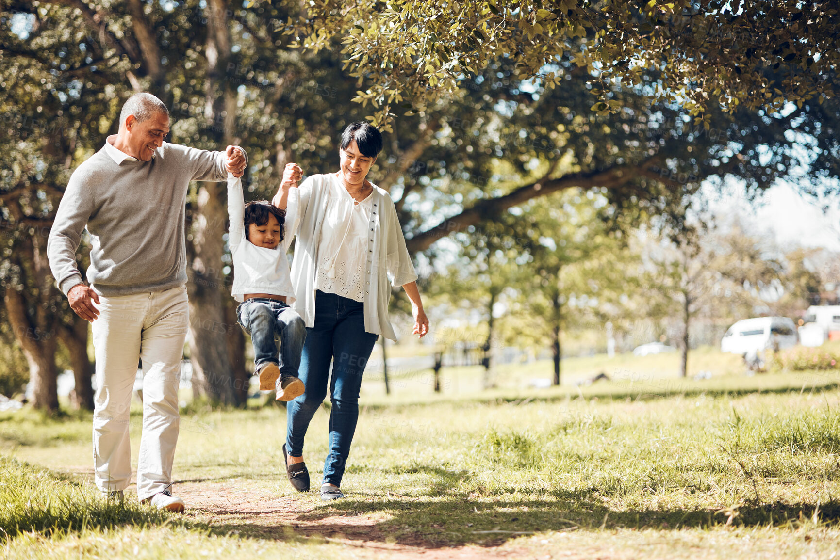 Buy stock photo Happy, holding hands and grandparents with child in park for playing, love and support. Swing, smile and freedom with family walking on nature path for fun, summer vacation and happiness together