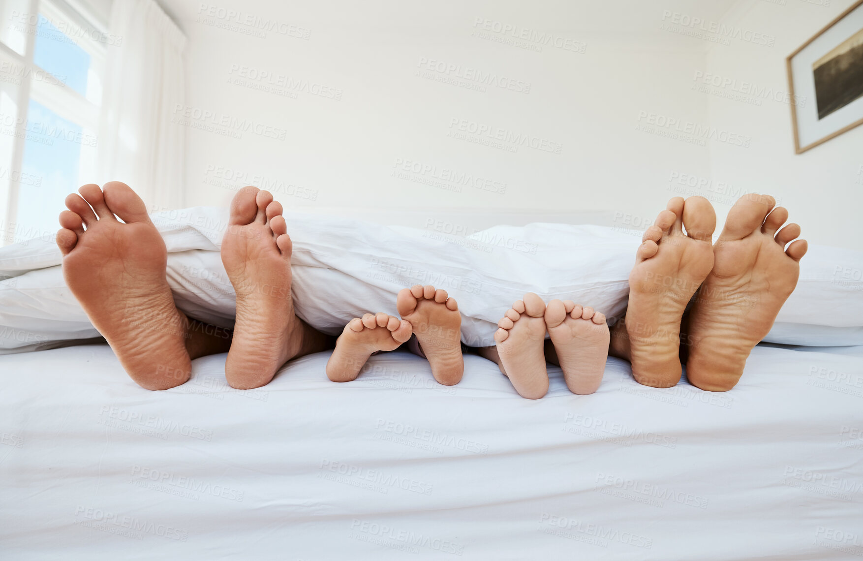 Buy stock photo Feet, family and sleep in bedroom in home, relax in peace and rest in blanket in the morning together. Barefoot, bed and father, mother and children with parents in comfort, bonding and care in house