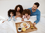 Parents, kids and breakfast in bed, morning or excited for love, bonding or care on holiday. Mother, papa and children in bedroom, food and smile together for nutrition, eating and happy family home