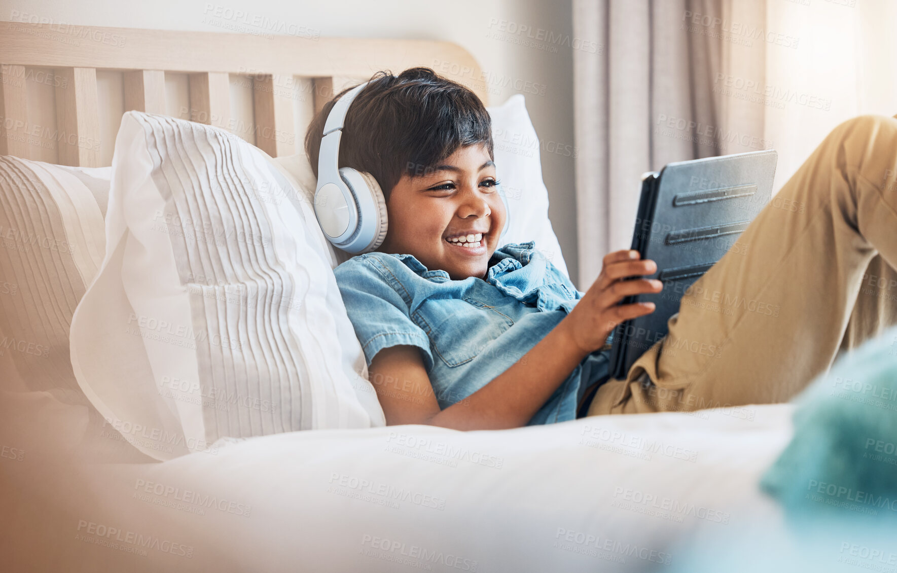 Buy stock photo Child, tablet and smile with headphones on bed for online games, watch movies or play educational app. Happy boy kid listening to multimedia, music or streaming cartoon in bedroom on digital tech 