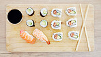 Sushi, top view and soy sauce with food on wood board, closeup with salmon and rice, healthy and luxury. Japanese cuisine, catering with lunch or dinner meal, chopsticks and seafood with nutrition