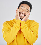 Smile, shy and hands on face of asian man in studio for in love, sweet or gesture on grey background. Happy, portrait and Japanese male model pose with emoji cheeks expression for romantic sign
