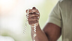 Rosary, man hands and prayer beads in a home with hop, christian praise and religion. Praying, necklace and worship in a house with hope, gratitude and spiritual guide for faith support and healing