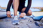 Hands tie shoes, beach and athlete start workout, training and kayak exercise outdoor. Sand, person and tying sneakers at ocean to prepare in fitness, sports and healthy body for wellness in summer.